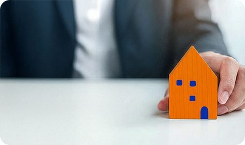image of a business man placing a wooden house toy on a table