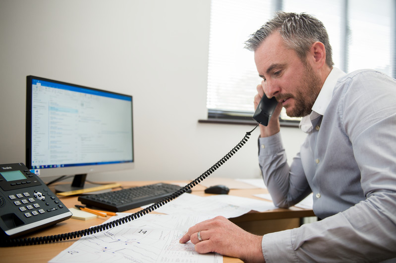 A man engaged in a phone conversation, earnestly conveying vital information to either a customer or a colleague.
