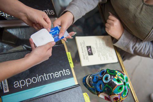 The scene depicts a customer completing a transaction by using a debit or credit card to make a payment for a service or product.