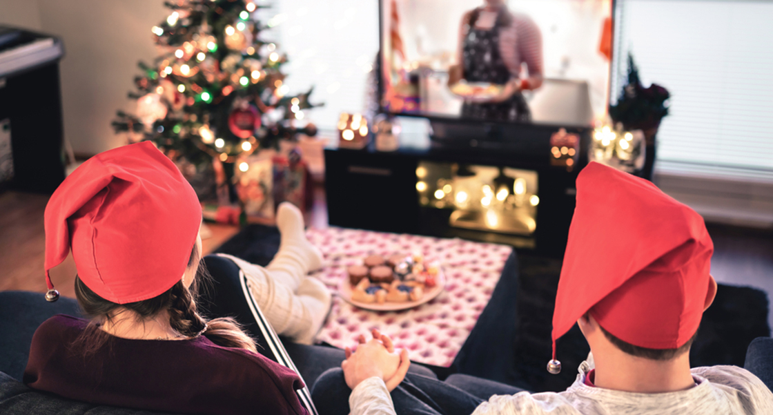 Couple holding hands and watching TV in festively decorated living room