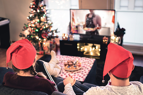 Couple holding hands and watching TV in festively decorated living room