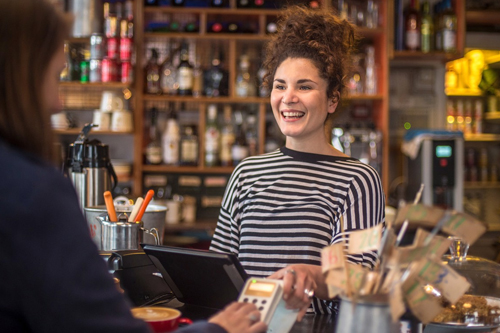 A heartwarming scene in a small and medium-sized business, where a customer is happily completing a payment for services. The shop assistant reciprocates the joy with a warm smile, creating a positive and pleasant interaction. 