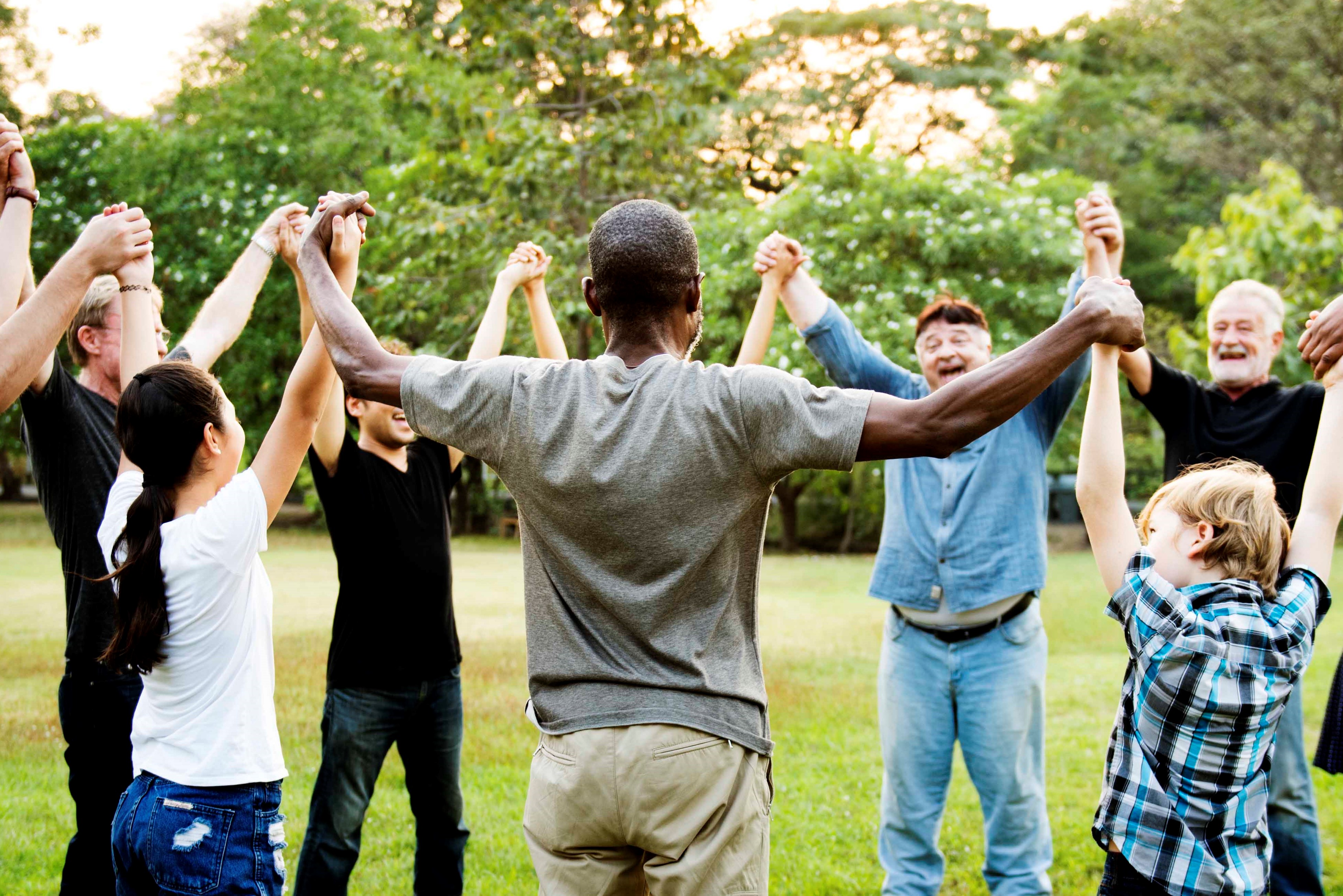 A group of people hold hands and raise them in the air while standing in a circle